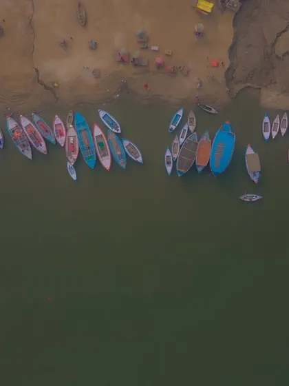 A fleet of colorful boats waiting for pilgrims and tourists on the banks of the Ganga. This top-down aerial shot turns the scene into a beautiful, abstract pattern.