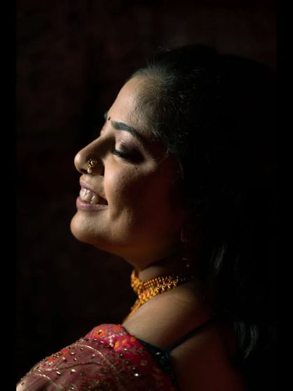 A close-up profile shot of the bride during her engagement. The soft side lighting beautifully illuminates her happy expression and traditional nath, creating a timeless and elegant portrait.