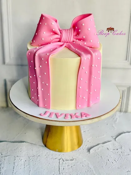 Because every celebration deserves a pretty bow. This cake is designed to look like a gift box, complete with a large, perfectly crafted pink fondant bow.