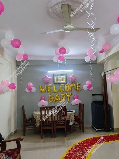 A simple "Welcome Baby" decoration at home with pink and white balloons floating on the ceiling.