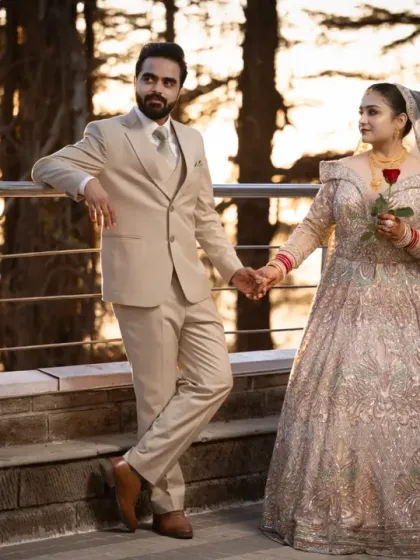 A full-length shot of the couple on a terrace overlooking the hills. This showcases their elegant reception attire and the beautiful destination setting.