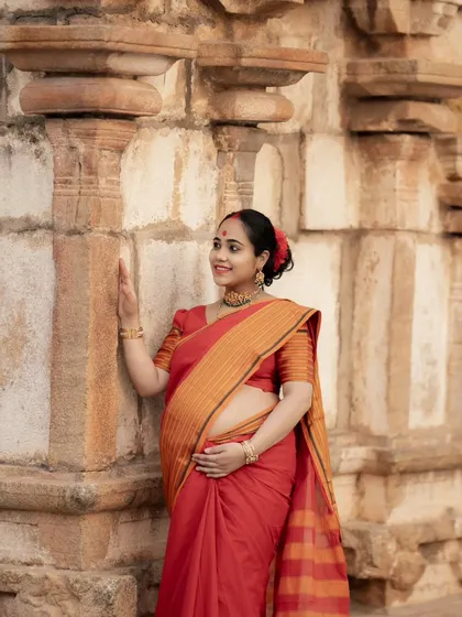 A solo portrait of the mother-to-be at a temple, gently touching the ancient stone walls. Her traditional attire and serene expression create a timeless image.