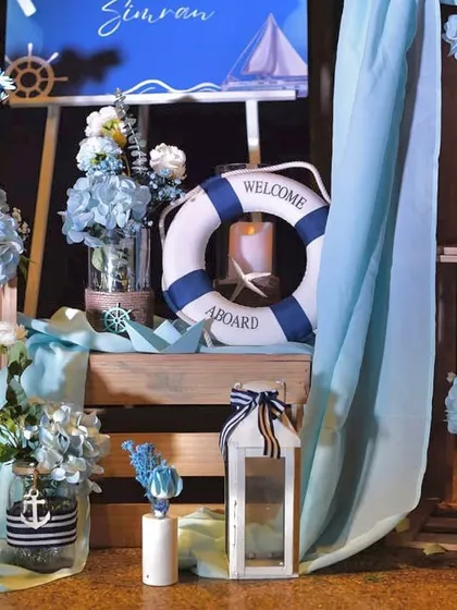 A welcome installation for the nautical-themed party, featuring a "Welcome Aboard" lifebuoy, wooden crates, and other seaside-inspired props.