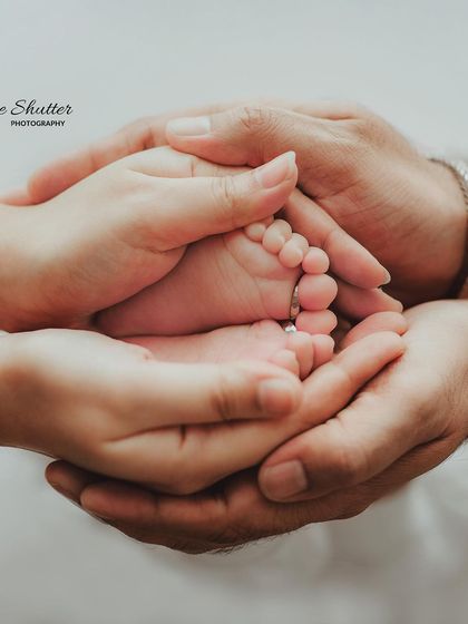 A beautiful shot of a baby's feet held securely in the hands of both parents, symbolizing family and protection.