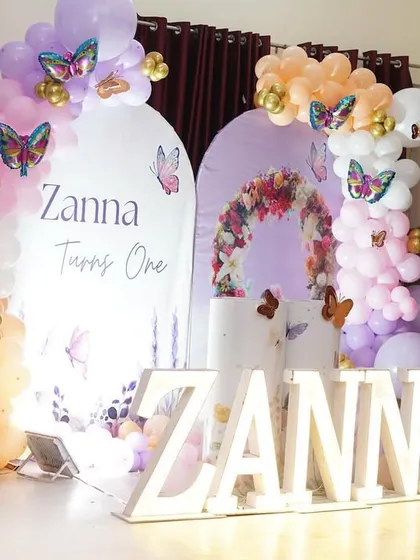 A dreamy butterfly and flower theme for Zanna's first birthday. We used dual arched backdrops, one with a floral wreath design, and marquee letters to create this enchanting setup.