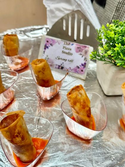 Crispy spring rolls served in a modern style. Each roll is placed in a small cup with dipping sauce, an elegant and mess-free way to serve a classic appetizer at any event.