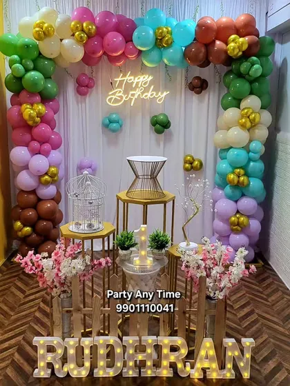 A very colorful balloon arch decoration for a fun and lively birthday party. This setup for "Rudhran" uses a mix of green, pink, blue, and brown balloons with light-up letters.
