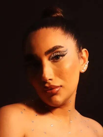 A portrait showcasing a creative makeup look with rhinestones scattered across the collarbones and a bold, glittery eye. This demonstrates how I extend makeup beyond the face to create a complete conceptual piece.