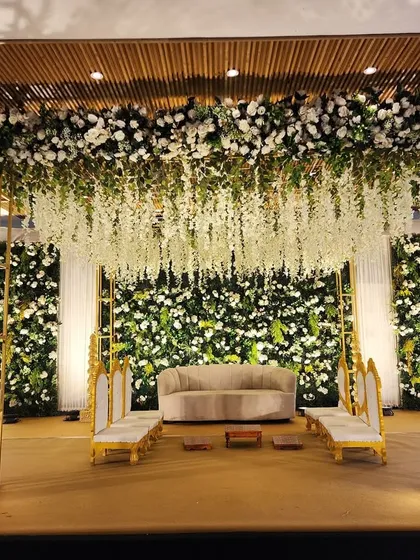 A full view of the green and white floral stage, showing the grand scale of the backdrop and the cascading wisteria ceiling treatment.