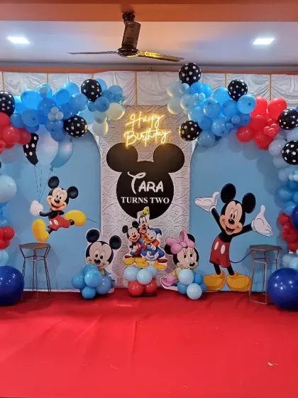 A Mickey and Minnie Mouse party backdrop with a neon "Happy Birthday" sign. The bright colors and familiar characters make it a hit with toddlers.