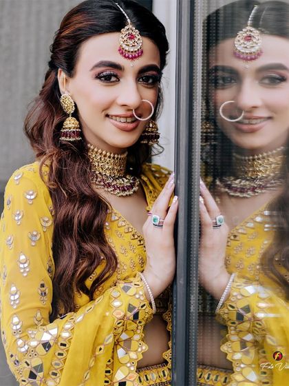 A close-up portrait of the bride, her reflection in the window adding a creative layer to this beautiful Mehendi day shot.