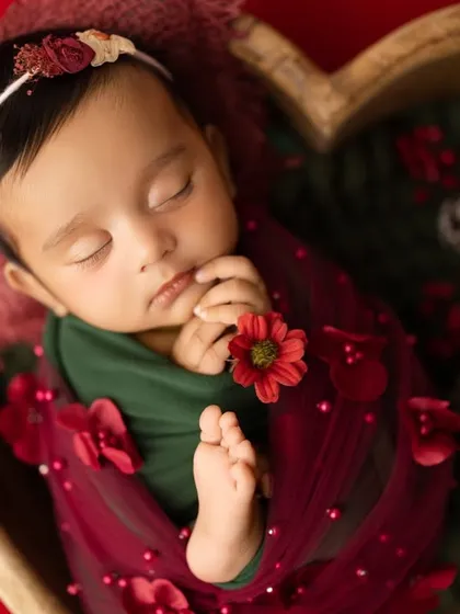 This portrait captures the peaceful sleep of a newborn, swaddled in festive red and green. The heart-shaped wooden bowl is one of the many props I have in my Navi Mumbai studio to create unique setups.
