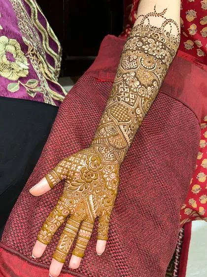 A single arm view of a classic Indian bridal design. The patterns are dense and full of traditional motifs like paisleys and checks.