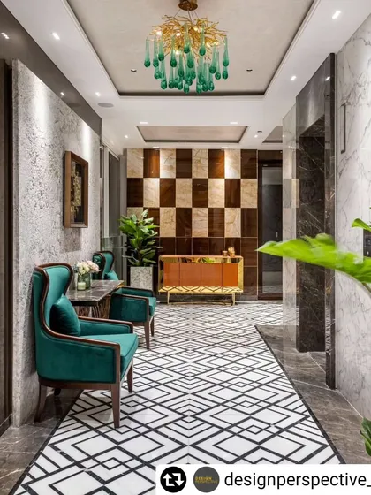 The entrance lobby of a luxury apartment sets the tone for the entire home. Here, we used bold geometric floor patterns, rich emerald green chairs, and a checkered wood-and-marble feature wall to make a grand first impression.