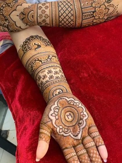 An elegant design featuring a peacock motif and the initial 'M' in the center of the palm, perfect for a bride or for festive occasions.