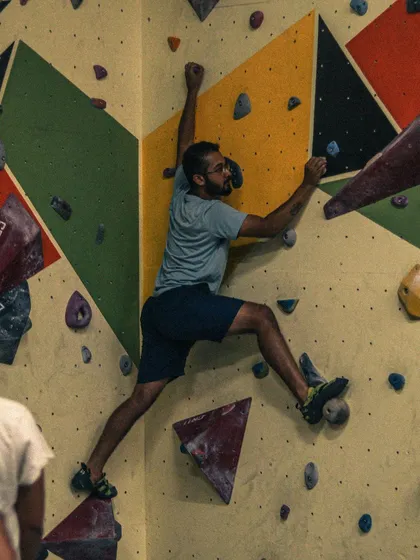 Bouldering is all about problem-solving on the wall. Here, a climber carefully plans his next move, using precise footwork and body positioning to navigate a route on our geometrically patterned wall.