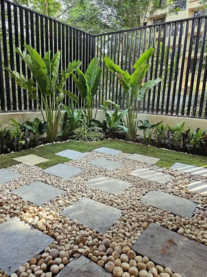 I designed this modern backyard corner to be super low maintenance but high on style. The combination of large stone pavers, smooth river pebbles, and tall Traveller's Palms creates a clean, tropical feel that's perfect for relaxing.