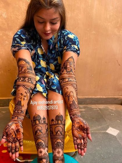 A full view of a bride with her hands and feet adorned with intricate story-telling mehndi. The designs are cohesive and tell a beautiful story.