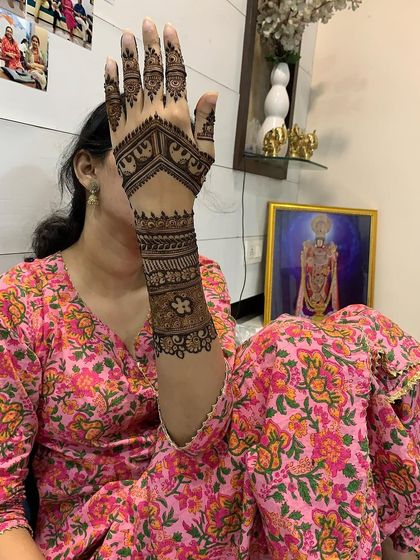 The same client showing a side view of her intricate elephant-themed mehndi. This pose highlights the detailed cuff and finger designs.