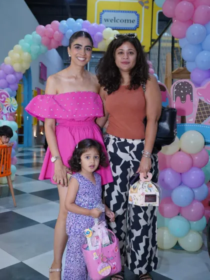 A beautiful family photo from a candy-themed birthday party. The pastel balloon arch provides a perfect, festive backdrop for capturing happy memories.