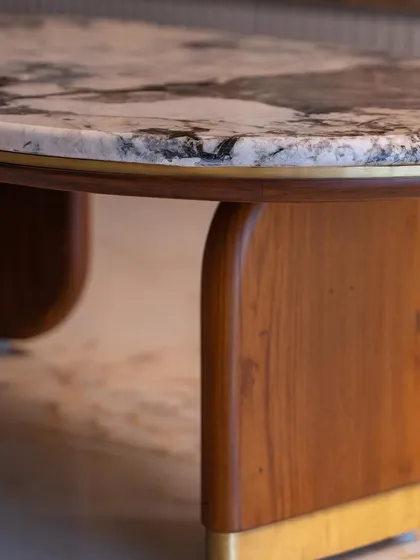 A detail shot capturing the elegant curve of the coffee table's wooden base and brass accent.