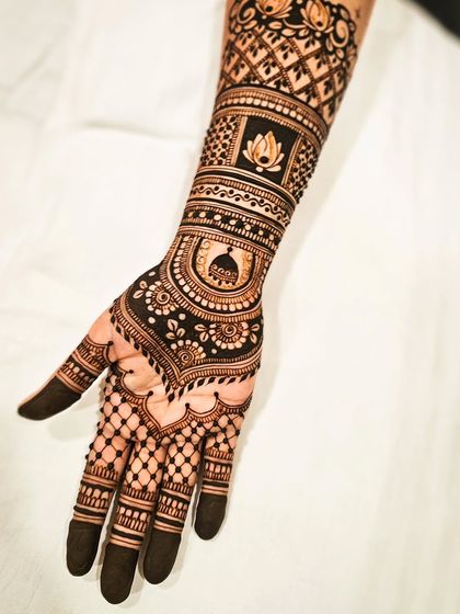 A close-up of the forearm, highlighting a custom dome element and a lotus motif, blending personal touches with traditional patterns.