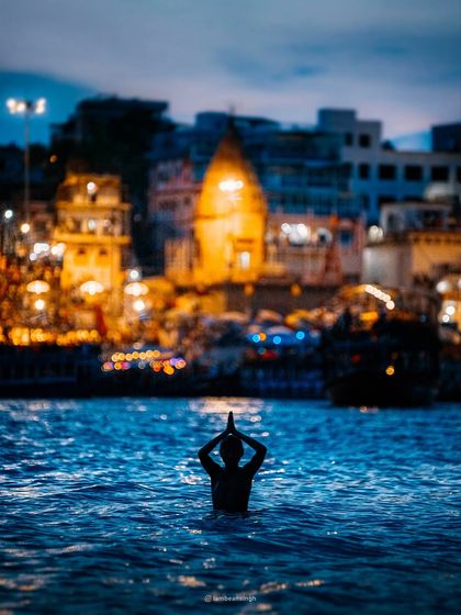 This iconic shot captures a moment of serene devotion as a person offers prayers in the Ganga, with the ancient temples of Varanasi forming a timeless backdrop.