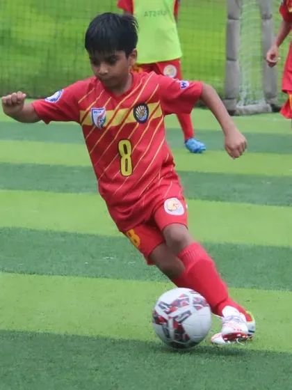 A U9 player dribbling with focus and determination.