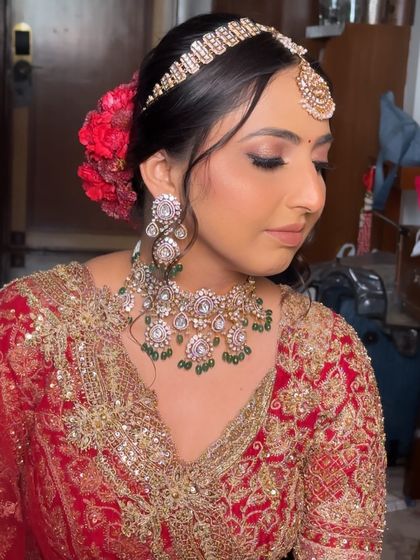 A close-up of the bride's stunning makeup and jewelry, complemented by the classic red floral updo.