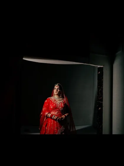 A wide shot of the bride, framed by darkness, which puts all the focus on her and the beautiful light she is standing in.
