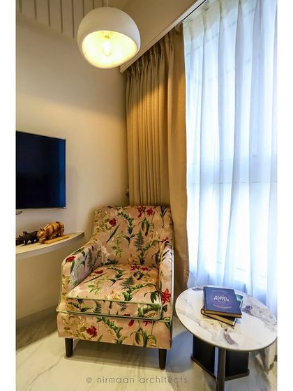 This guest bedroom features a beautiful floral armchair, adding a touch of color and pattern to the neutral space. It’s a cozy reading nook for visitors to enjoy.