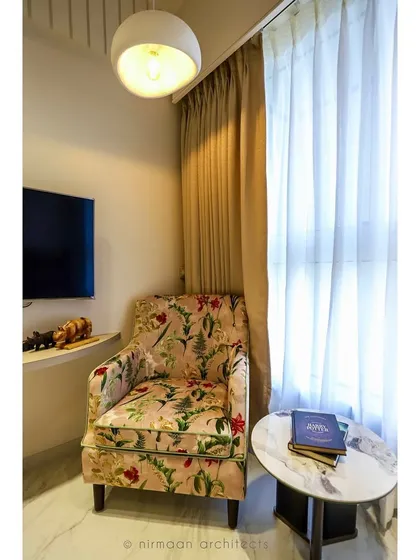 This guest bedroom features a beautiful floral armchair, adding a touch of color and pattern to the neutral space. It’s a cozy reading nook for visitors to enjoy.