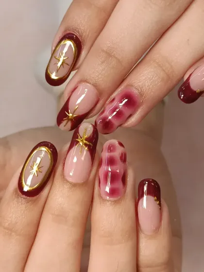 Both hands together, showing the full mixed-media nail art set. The combination of French tips, blooming gel, and gold embellishments creates a cohesive yet unique look.
