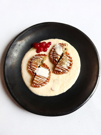 Another view of the pistachio chandrakala, a sweet pastry filled with nuts and served on a bed of thickened milk, or rabri.