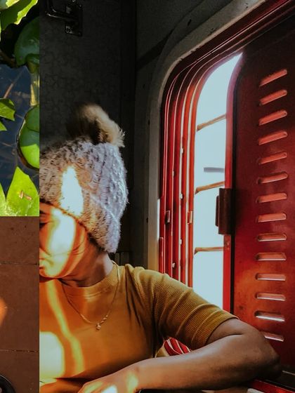 A person on a train, their face partially covered by the beautiful striped shadows cast by the window grille.