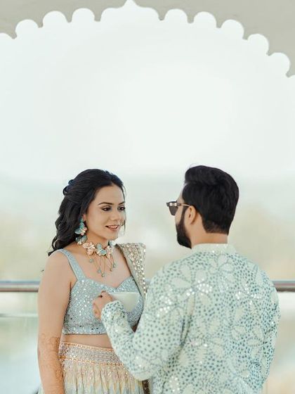 A beautifully framed shot of the couple under a white archway, their interaction feeling natural and romantic.