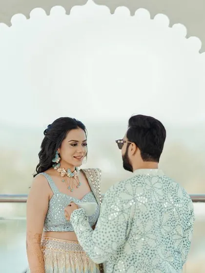 A beautifully framed shot of the couple under a white archway, their interaction feeling natural and romantic.