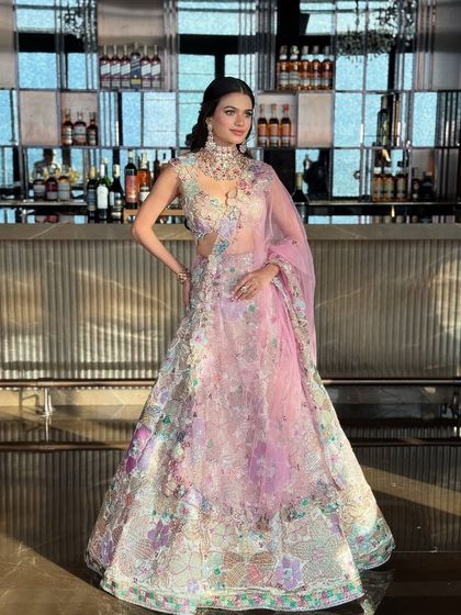 This shot captures the full essence of the summer bridal look, with the pastel lehenga standing out against the warm tones of the bar.