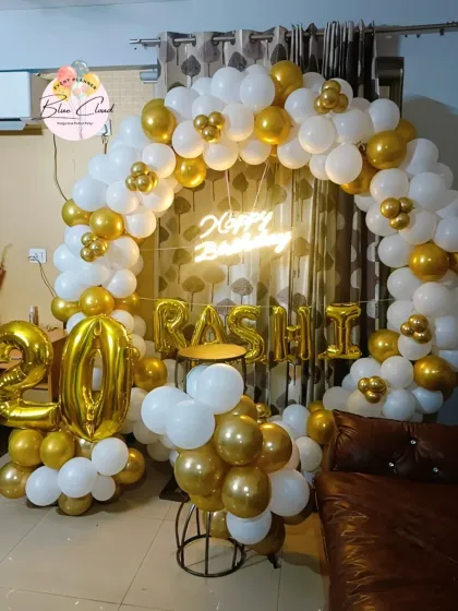 A chic white and gold balloon ring with a neon sign and foil letters for a 20th birthday.