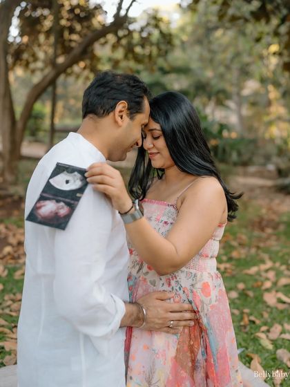 Sharing a secret with their little one. This intimate moment of the couple looking at their ultrasound scan together in the park is pure magic.
