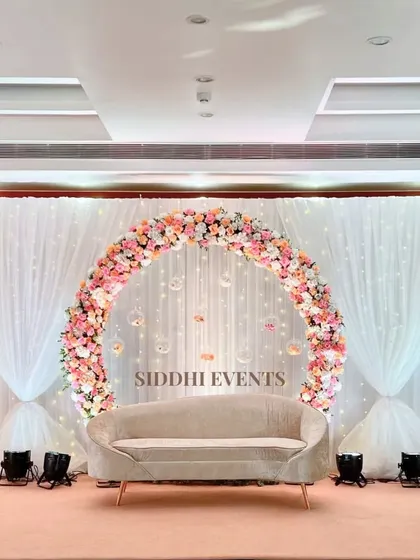 This dreamy ring ceremony setup features a circular floral arch with hanging glass baubles, creating a delicate and magical focal point behind the couple's seating.