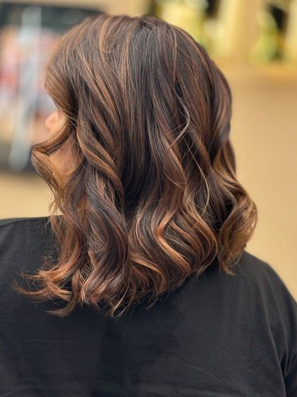 A close-up back view of a client's creative color. The blend of warm tones and soft waves creates a rich, dimensional look that is full of personality.