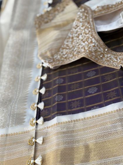 A white and gold blouse with delicate tassels on the back.