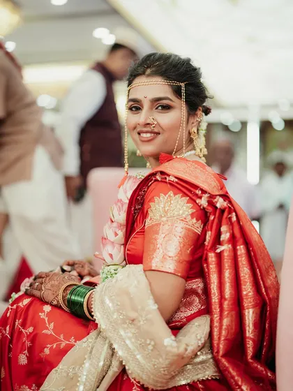 The bride seated during her ceremony, looking elegant and poised in her red wedding saree.