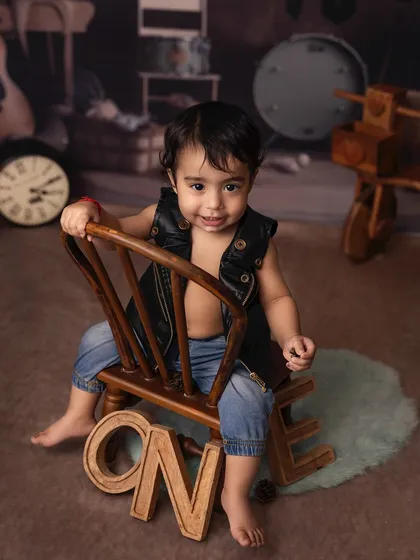 One year old and born to rock! This little guy is celebrating his first birthday with a cool, confident pose in his music-themed studio setup.