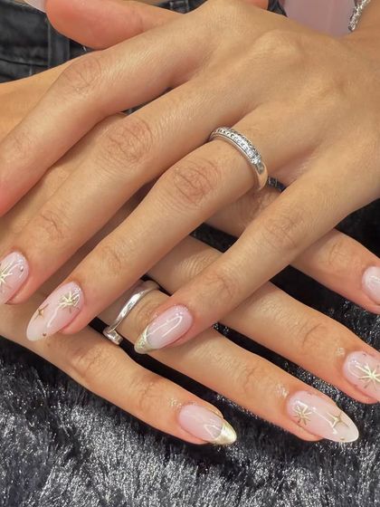 A celestial-inspired design that's both elegant and modern. This set features a sheer, shimmery base with delicate gold French tips and hand-painted gold starbursts.