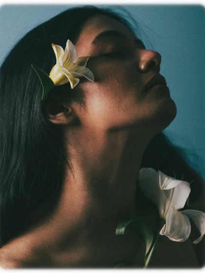 This profile shot is all about elegance and grace. The flowers are placed delicately in the model's hair, and her tilted-back head creates a beautiful, long line along her neck. The lighting is soft and ethereal.