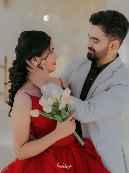 A tender moment where the groom caresses the bride's face as she holds a bouquet of white tulips.