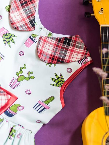 A quirky and fun design for a girl with a unique personality. This dress features a cute cactus print, with contrasting plaid accents on the collar and a matching bow.