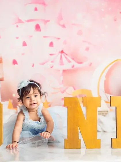 This little one crawls through a dreamy pink wonderland, complete with fluffy clouds and golden 'ONE' letters for her milestone photoshoot.